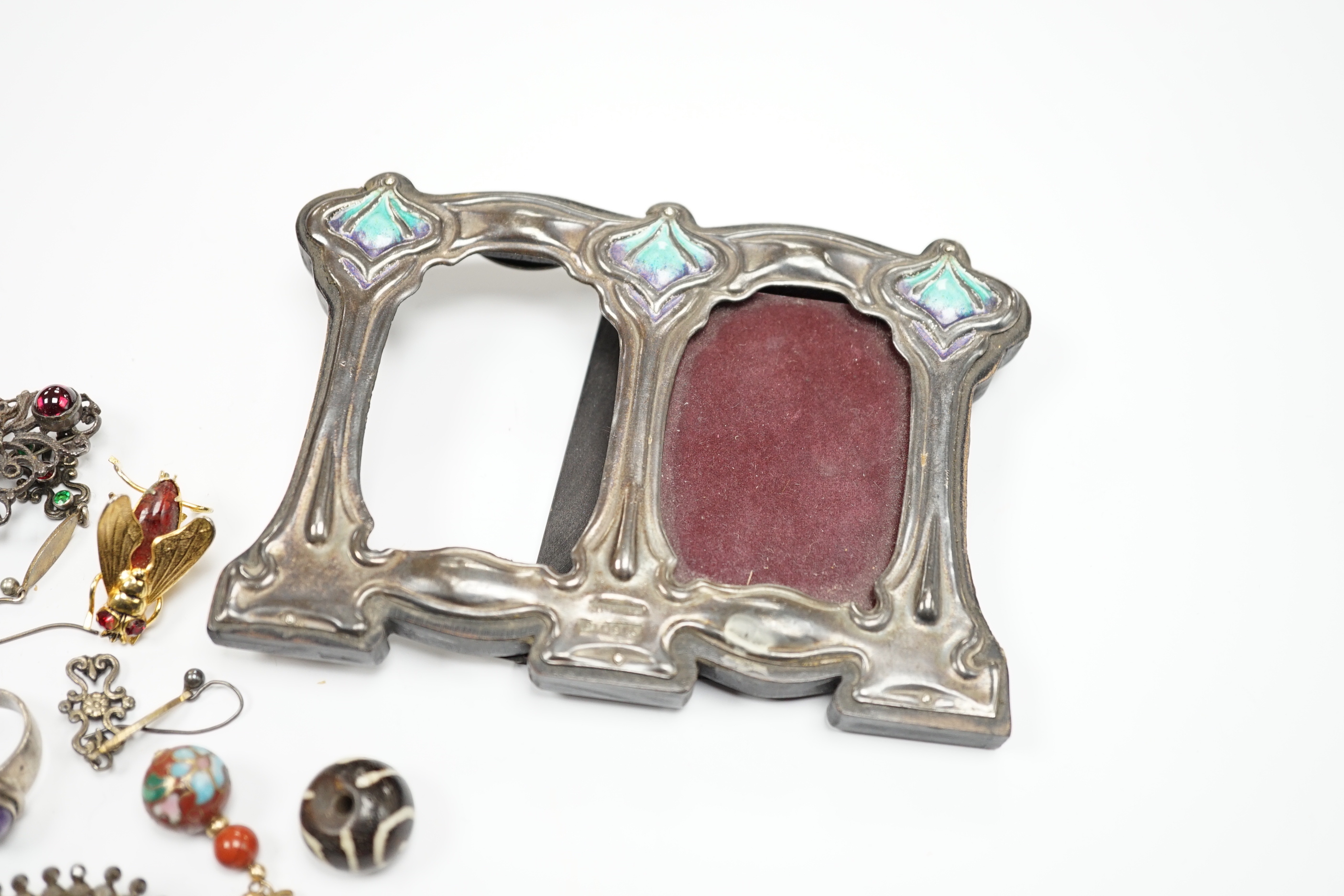 An Art Nouveau style sterling and enamelled double photograph frame, width 11.3cm, together with sundry jewellery including an Austro-Hungarian style necklace, white metal and cabochon amethyst set ring(stamped silver) e